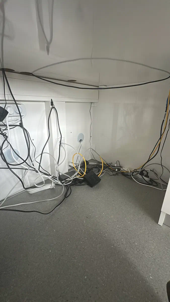Vorher: unter der Anmeldung. Netzteile, Verlängerungen und Netzwerkkabel lagen lose am Boden.